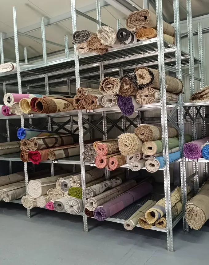 Police sa smotanim tepisima u različitim bojama i šarama u skladištu